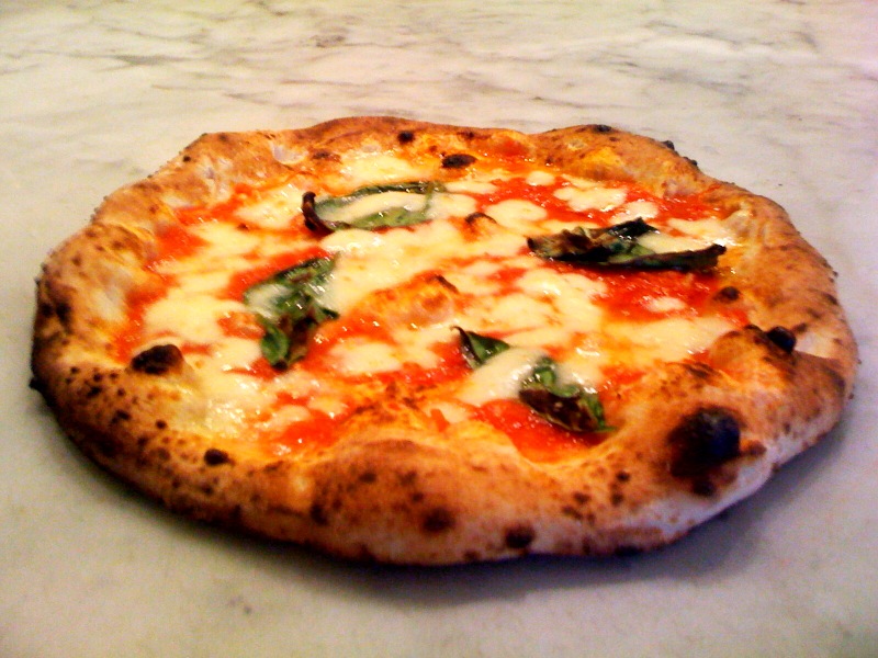 Napolitansk margheritapizza med bränd kant, mozzarella och basilika